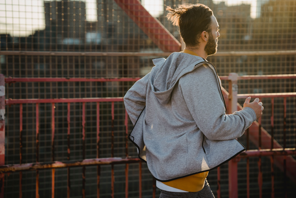 Runner jogging on an urban bridge during sunrise