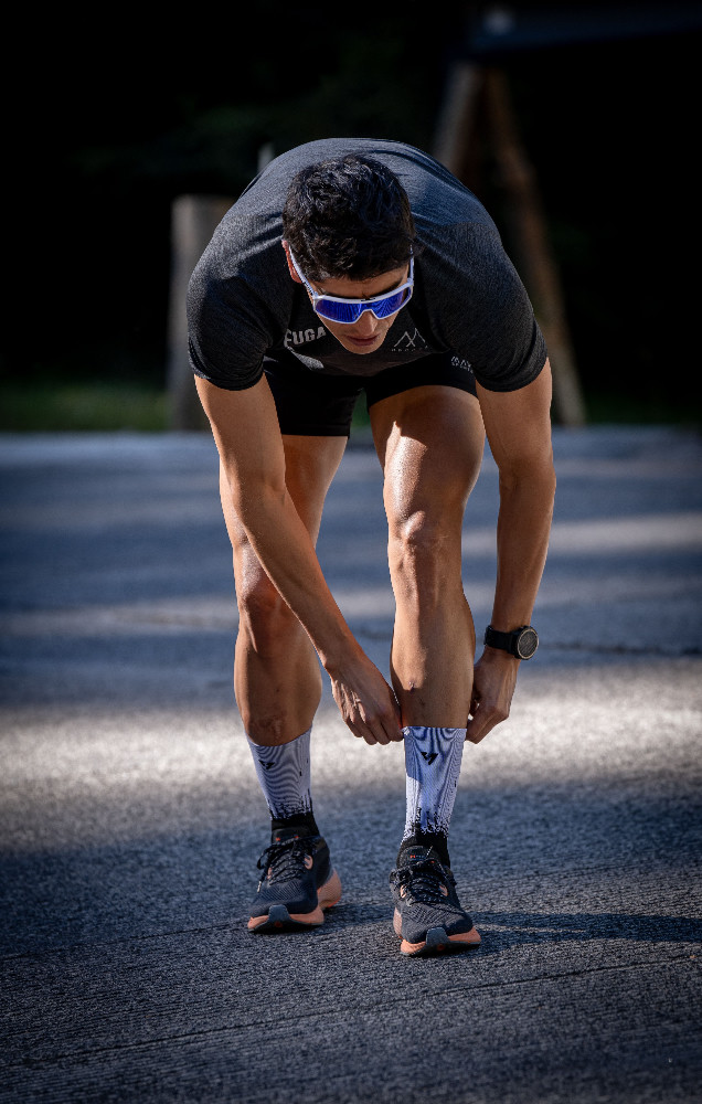 Athlete preparing for a run by adjusting socks outdoors