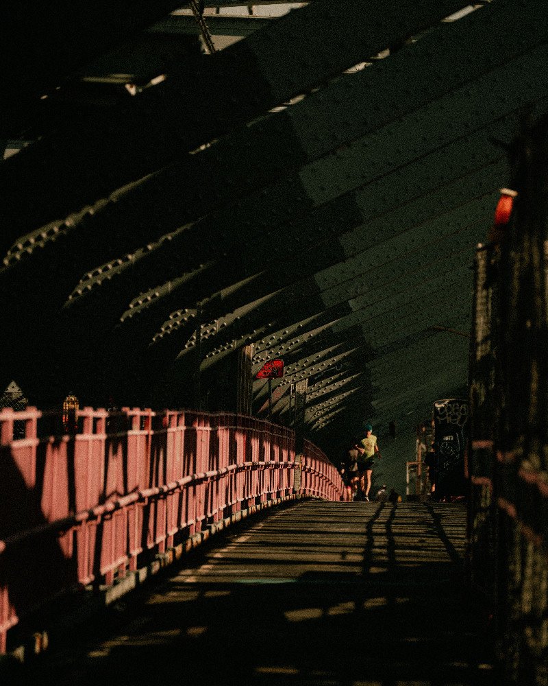 Runner moving through dramatic bridge shadows in a city